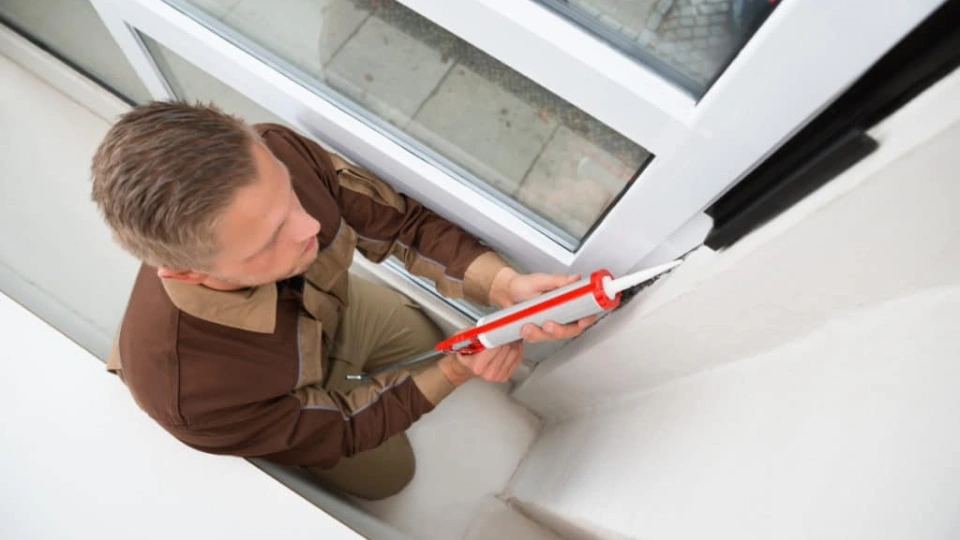 Application de spray silicone sur les joints en caoutchouc d'une fenêtre à Anderlecht pour prévenir les fuites d'air et le gel en hiver.